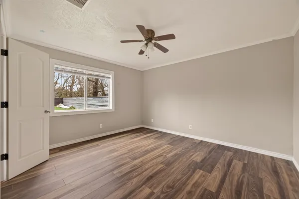 a view of an empty room with wooden floor and a window