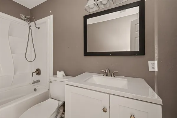 a bathroom with a sink vanity mirror toilet and bathtub