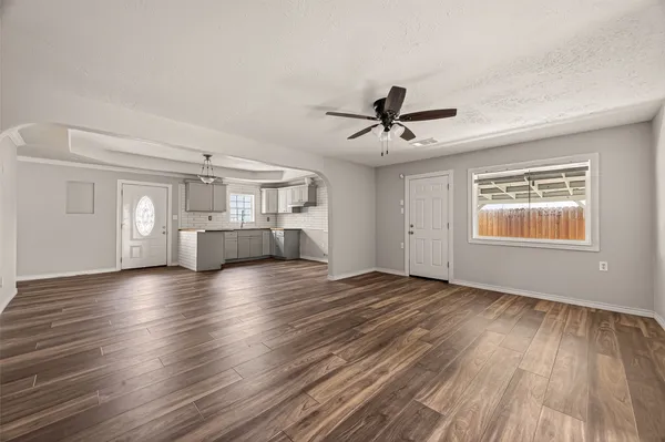 a view of empty room with wooden floor and fan
