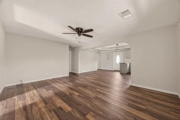 a view of empty room with wooden floor and ceiling fan