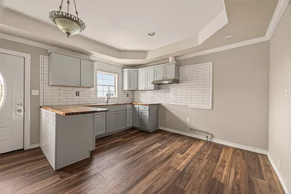 a kitchen with granite countertop wooden floors stainless steel appliances a sink and a window