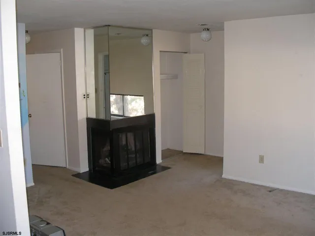 a view of an empty room with a window and a fireplace