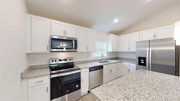 a kitchen with stainless steel appliances granite countertop a sink stove and refrigerator