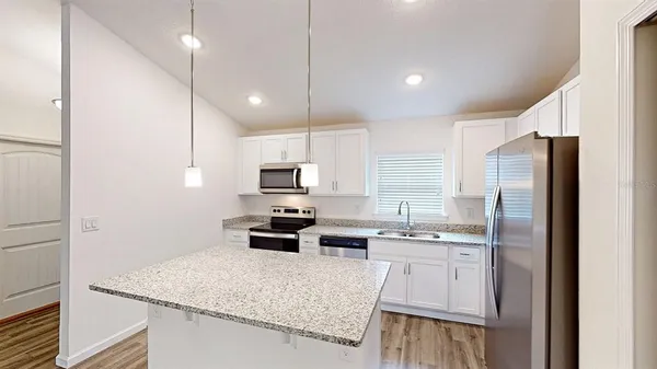 a kitchen with stainless steel appliances granite countertop a sink refrigerator and microwave