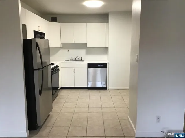 a kitchen with a refrigerator sink and cabinets
