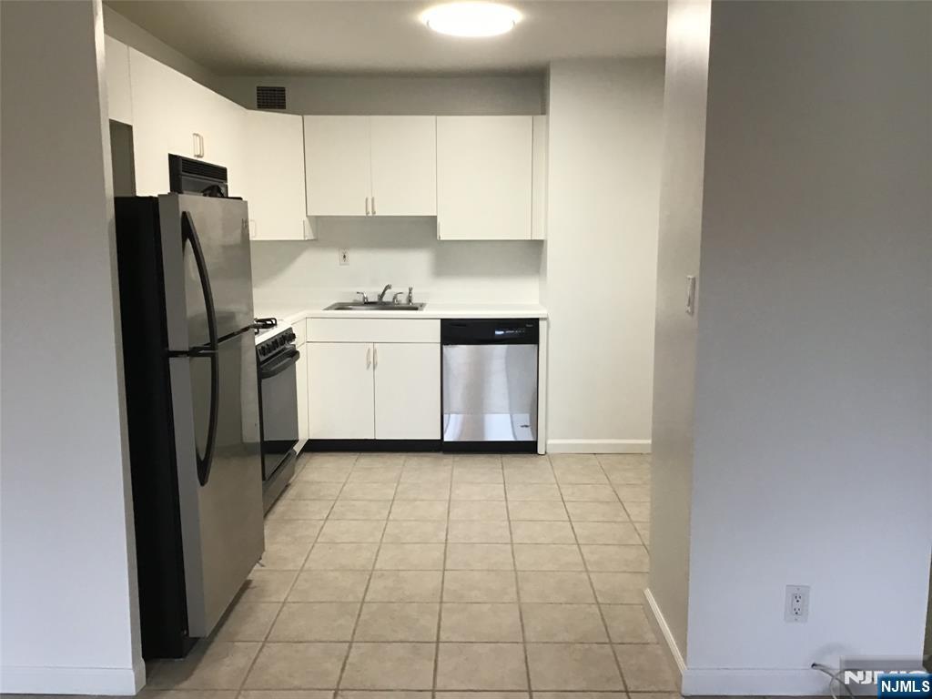 1203 River Road, Unit 21M Edgewater, NJ 07020 - Photo 3 of 12 a kitchen with a refrigerator sink and cabinets