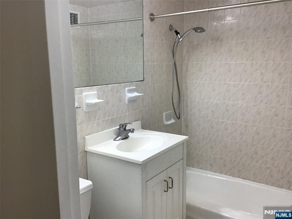 1203 River Road, Unit 21M Edgewater, NJ 07020 - Photo 6 of 12 a bathroom with a sink a shower and a mirror