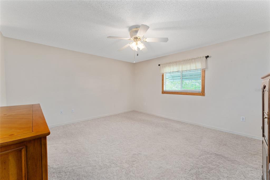 9499 Southeast 174th Loop Summerfield, FL 34491 - Photo 32 of 46 an empty room with a window and a ceiling fan