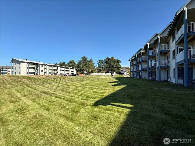 a view of a large pool with lawn chairs and a big yard