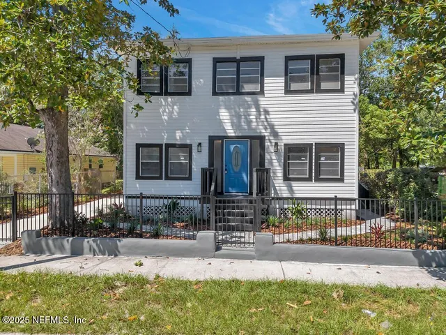 a view of a house with a small yard and wooden fence
