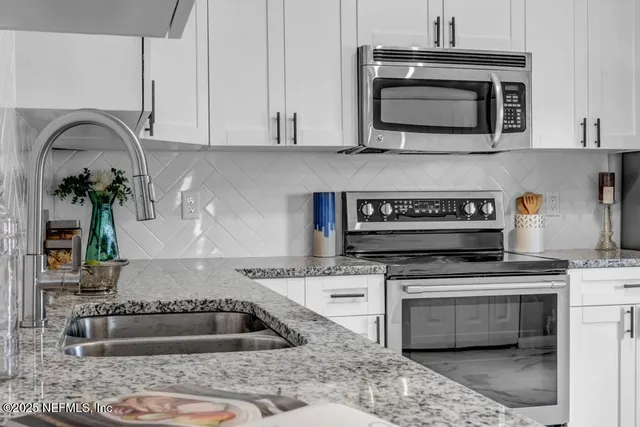 a kitchen with granite countertop a stove and a microwave
