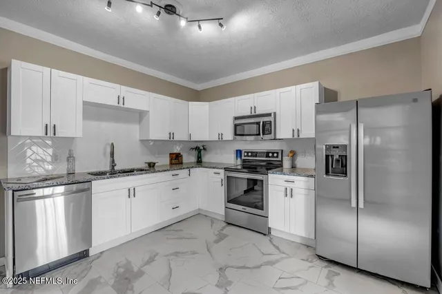 a kitchen with granite countertop white cabinets and stainless steel appliances
