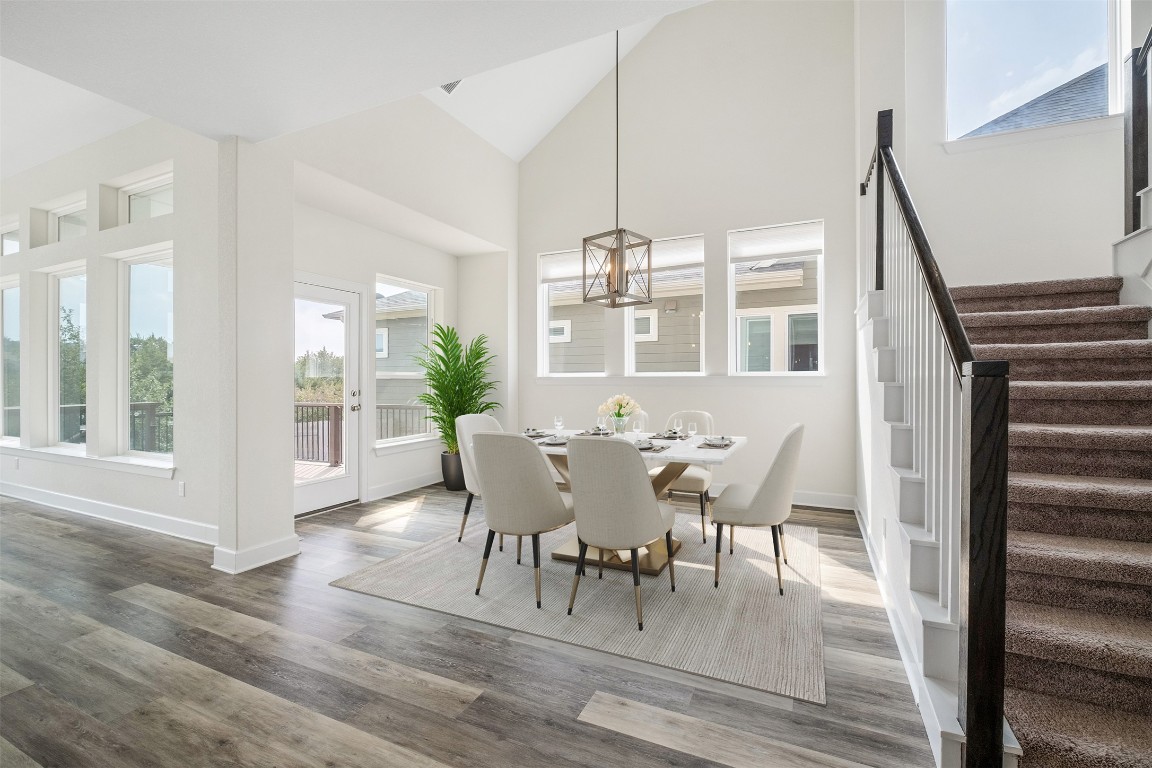 748 Hazy Hills Loop Dripping Springs, TX 78620 - Photo 12 of 40 Dining room featuring high vaulted ceiling, stairs, wood finished floors, and a chandelier