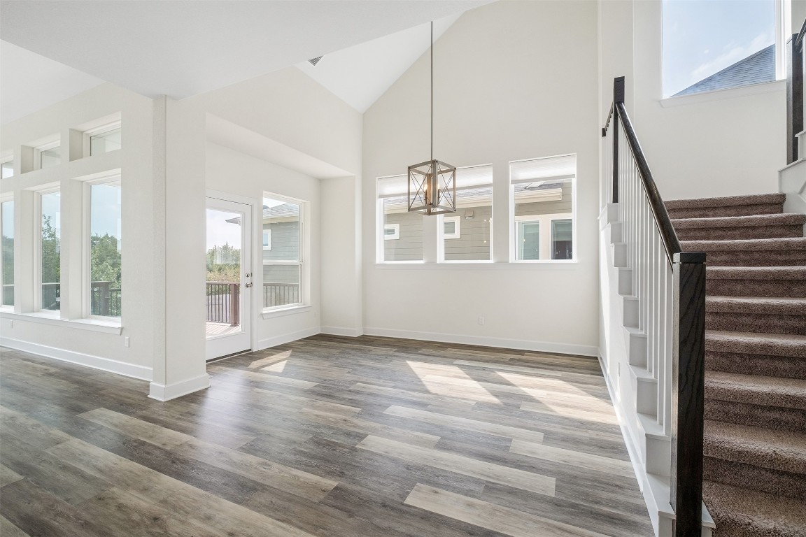 748 Hazy Hills Loop Dripping Springs, TX 78620 - Photo 13 of 40 Unfurnished dining area with high vaulted ceiling, stairway, wood finished floors, and a chandelier