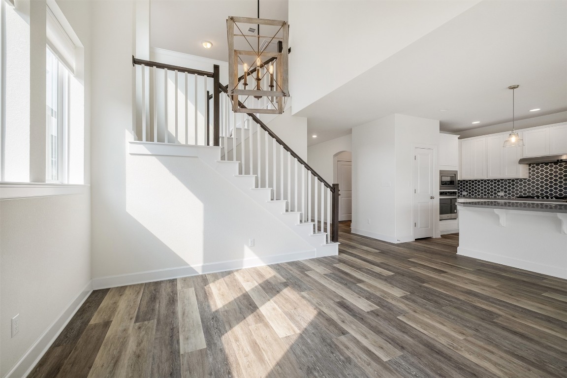 748 Hazy Hills Loop Dripping Springs, TX 78620 - Photo 14 of 40 Unfurnished living room featuring stairway, dark wood-type flooring, arched walkways, and recessed lighting