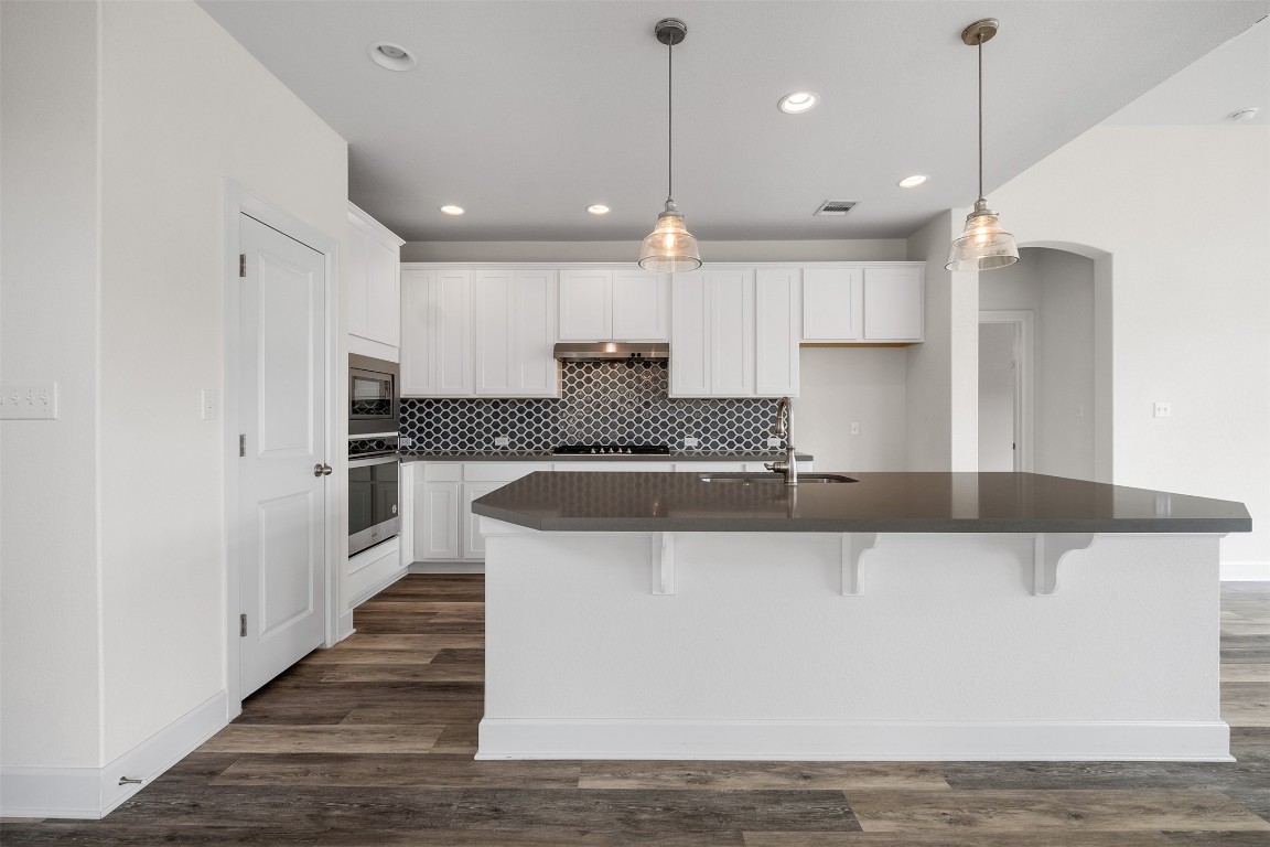 748 Hazy Hills Loop Dripping Springs, TX 78620 - Photo 15 of 40 Kitchen with white cabinets, a kitchen breakfast bar, decorative light fixtures, and recessed lighting