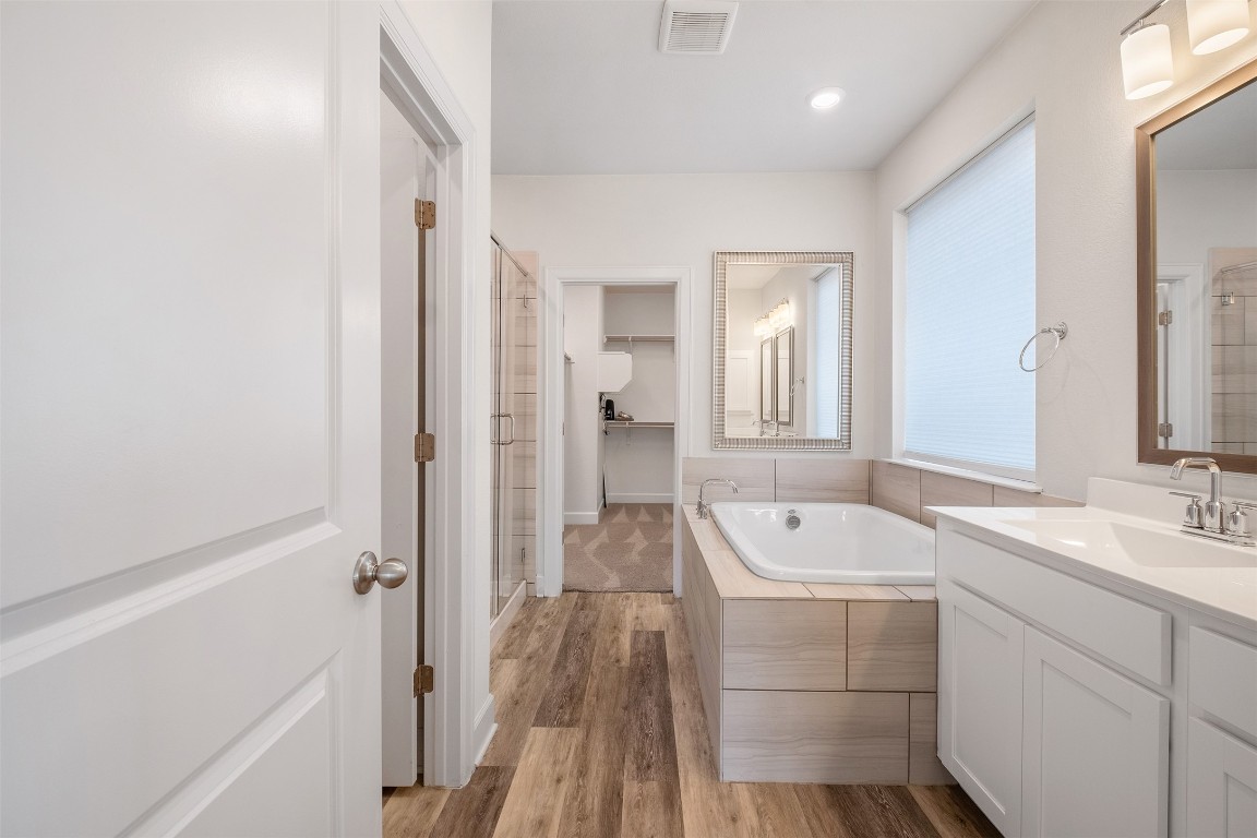 748 Hazy Hills Loop Dripping Springs, TX 78620 - Photo 27 of 40 Full bathroom with a bath, vanity, light wood finished floors, a walk in closet, and a shower stall