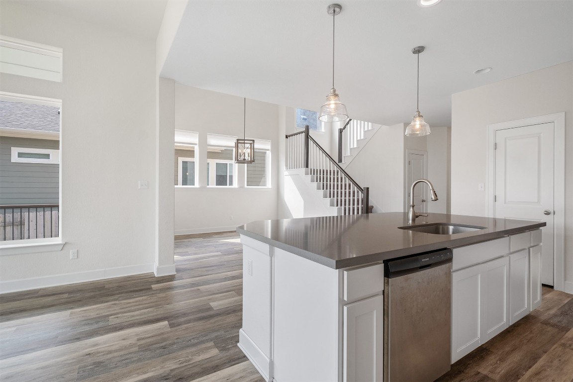 748 Hazy Hills Loop Dripping Springs, TX 78620 - Photo 30 of 40 Kitchen featuring pendant lighting, white cabinetry, stainless steel dishwasher, a kitchen island with sink, and dark wood-type flooring