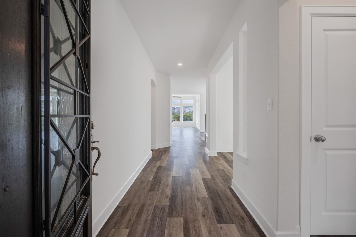 748 Hazy Hills Loop Dripping Springs, TX 78620 - Photo 3 of 40 Hallway with dark wood-style floors, recessed lighting, and arched walkways