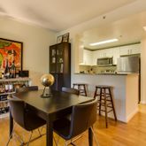 a kitchen with stainless steel appliances kitchen island granite countertop a table chairs and a refrigerator