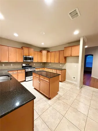 a kitchen with stainless steel appliances granite countertop a stove a sink and a microwave