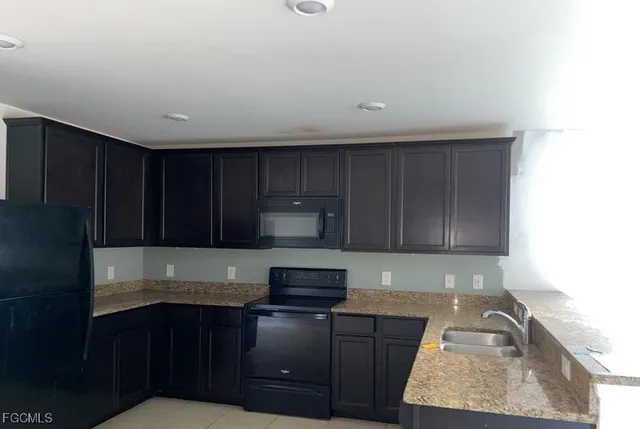 a kitchen with granite countertop stainless steel appliances wooden cabinets and a sink