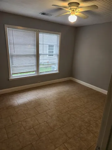 an empty room with windows and fan