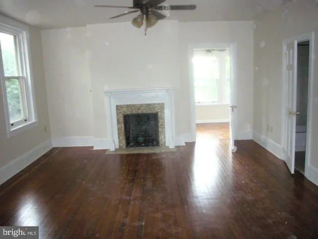 an empty room with wooden floor fireplace and windows