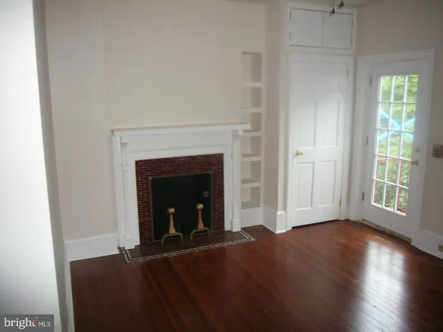 a view of a livingroom with wooden floor and a fireplace