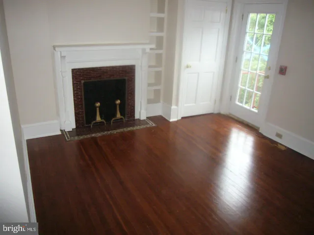 an empty room with wooden floor fireplace and windows