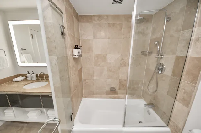 a bathroom with a tub shower vanity and a sink