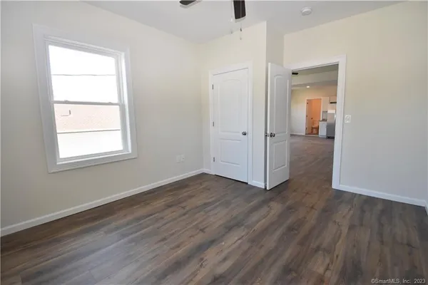 an empty room with wooden floor cabinet and windows