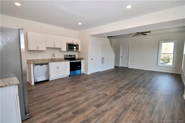 a view of a kitchen with wooden floor and a ceiling fan