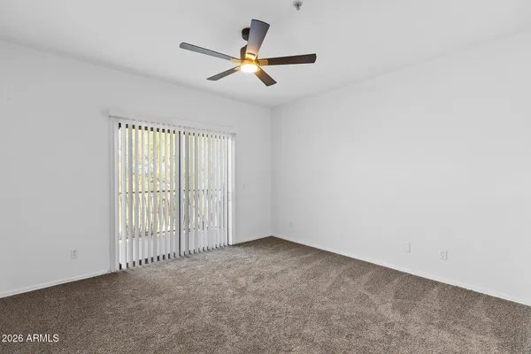 an empty room with a window and a ceiling fan