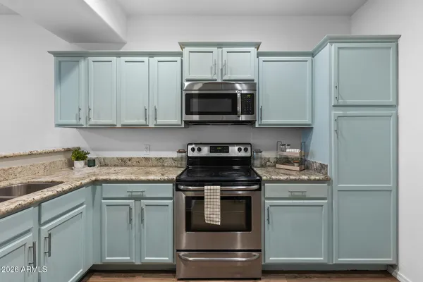 a kitchen with granite countertop a refrigerator and a stove top oven