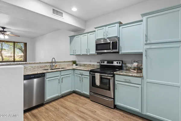 a kitchen with stainless steel appliances granite countertop white cabinets and a stove top oven