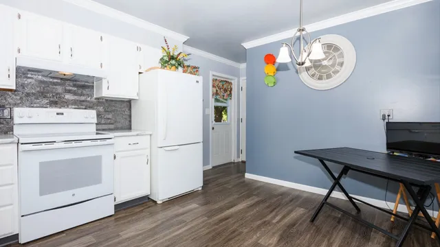 a white kitchen with a stove a refrigerator and a dining table