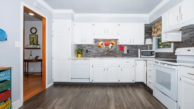 a kitchen with granite countertop white cabinets and wooden floor