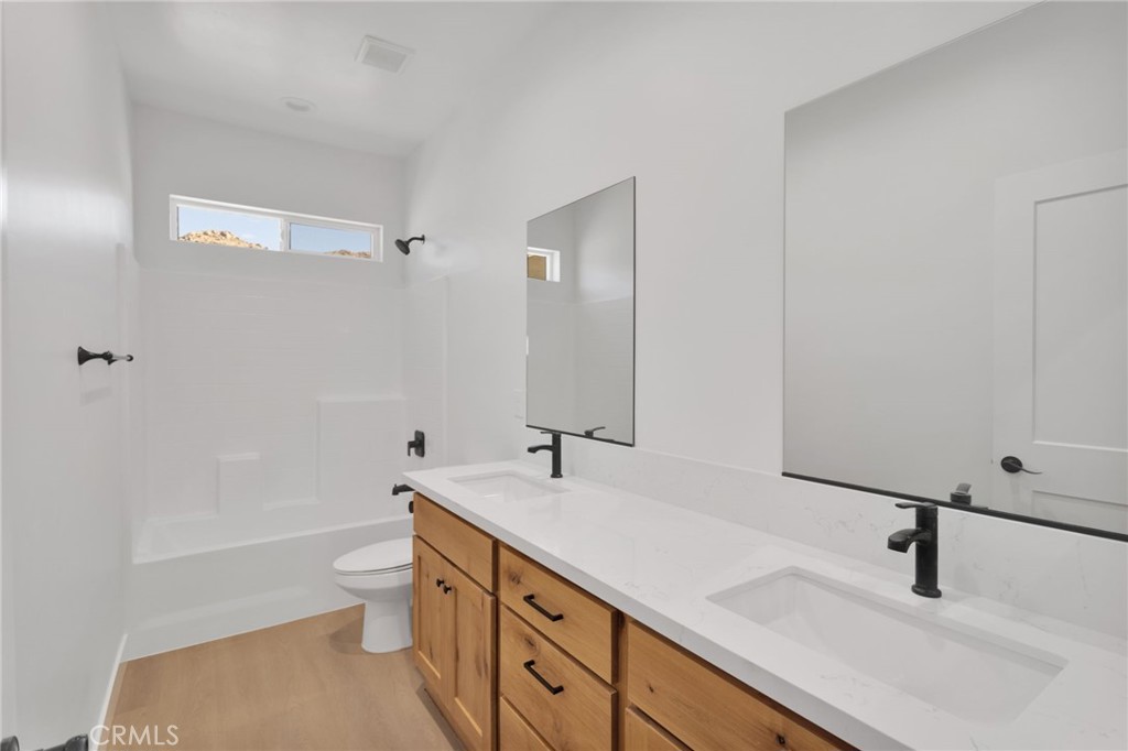 15561 Desert Star Road Apple Valley, CA 92307 - Photo 15 of 22 a bathroom with a double vanity sink a toilet and a tub