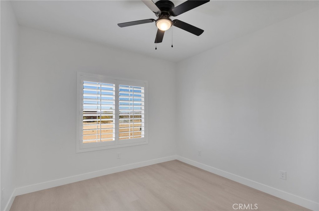 15561 Desert Star Road Apple Valley, CA 92307 - Photo 17 of 22 an empty room with a window and a fan