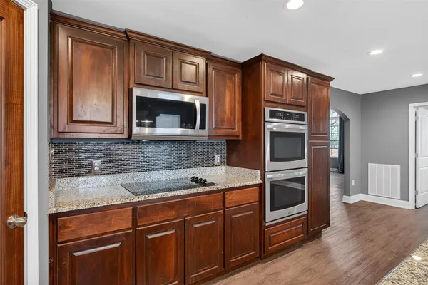 a kitchen with granite countertop a stove microwave and refrigerator