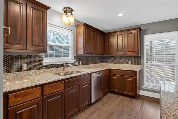 a kitchen with stainless steel appliances granite countertop wooden cabinets a sink and dishwasher with wooden floor