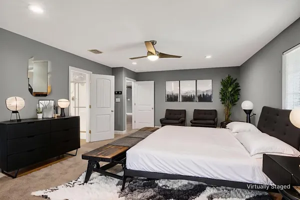 a large bedroom with bed table chair and window