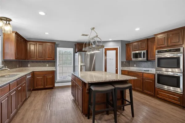 a kitchen with granite countertop kitchen island wooden cabinets and stainless steel appliances