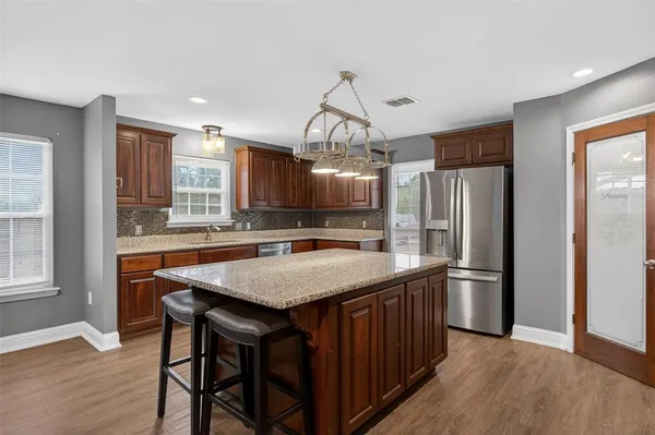 a kitchen with stainless steel appliances granite countertop a kitchen island and a refrigerator
