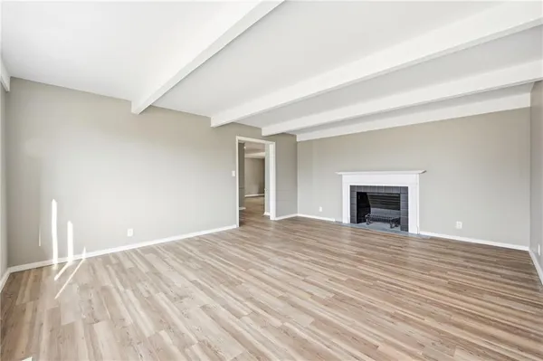 a view of empty room with wooden floor and fireplace