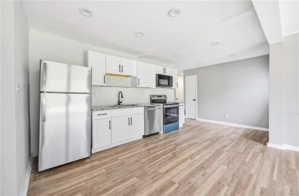 a kitchen with a refrigerator a stove top oven and white walls