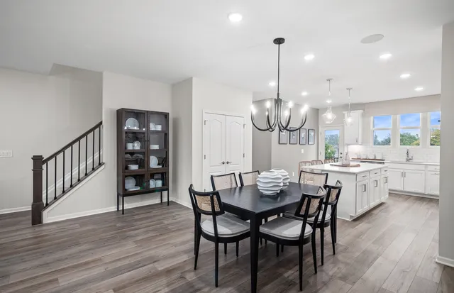 a dining room with wooden floor a chandelier a wooden table and chairs