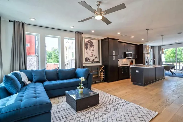 a living room with furniture kitchen view and a large window