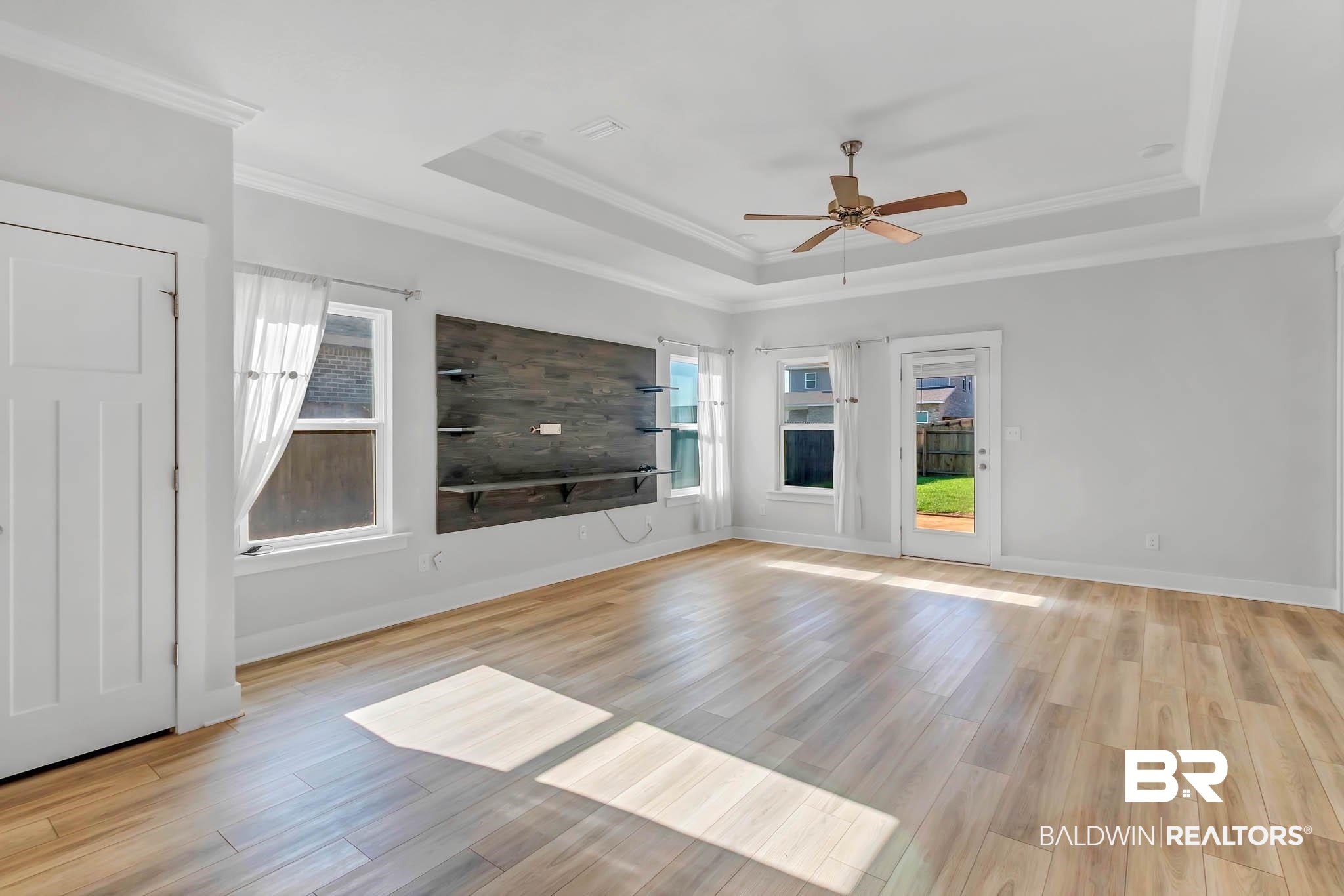 16461 Prado Loop Loxley, AL 36551 - Photo 8 of 78 Unfurnished living room featuring a tray ceiling, light wood-type flooring, crown molding, and ceiling fan